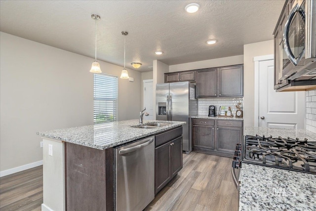 17719 Jackson Ridge Way, Nampa, ID 83687 - kitchen with appliances with stainless steel finishes, a sink, dark brown cabinets, light wood-type flooring, and decorative backsplash