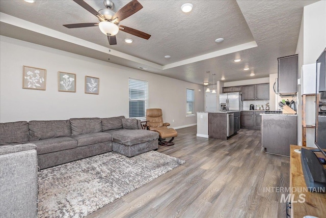 17719 Jackson Ridge Way, Nampa, ID 83687 - living room with a tray ceiling, a textured ceiling, a ceiling fan, dark wood finished floors, and baseboards