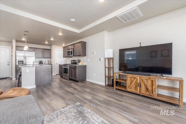 17719 Jackson Ridge Way, Nampa, ID 83687 - kitchen featuring stainless steel appliances, open floor plan, a textured ceiling, dark brown cabinetry, and wood finished floors