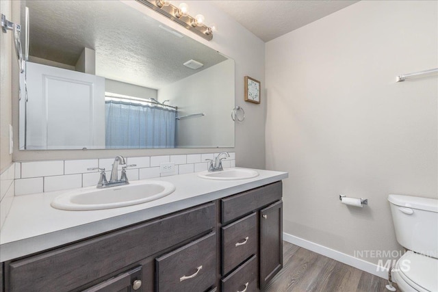 17719 Jackson Ridge Way, Nampa, ID 83687 - bathroom featuring toilet, baseboards, wood finished floors, double vanity, and a textured ceiling