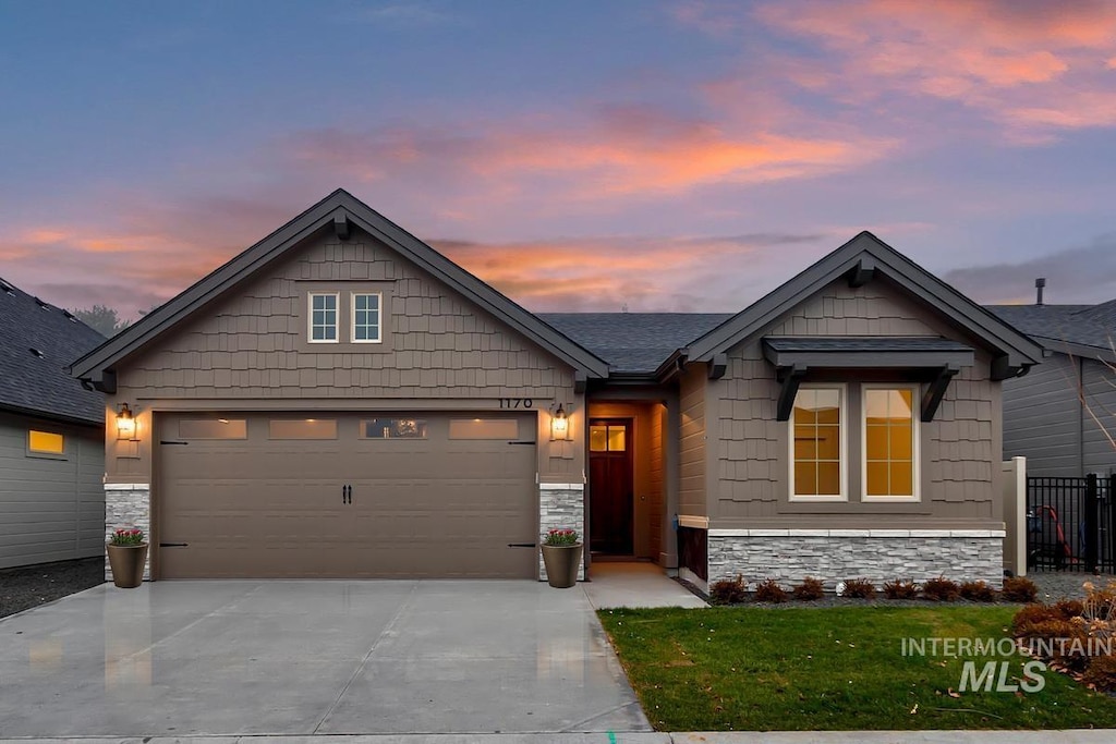 craftsman house with stone siding, concrete driveway, a garage, and fence