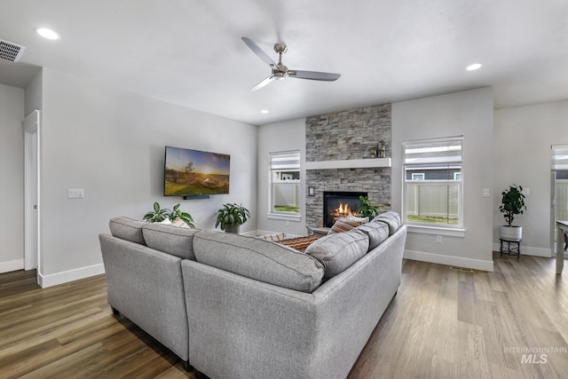 living area featuring a fireplace, baseboards, a ceiling fan, and wood finished floors