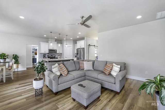 living area featuring wood finished floors, ceiling fan, recessed lighting, and a barn door