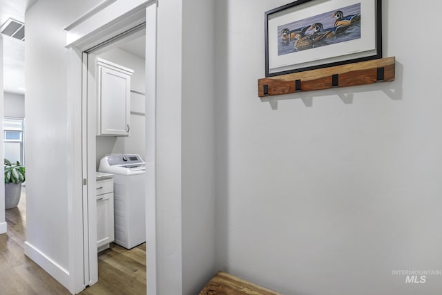 corridor featuring washer / clothes dryer, light wood-type flooring, and visible vents