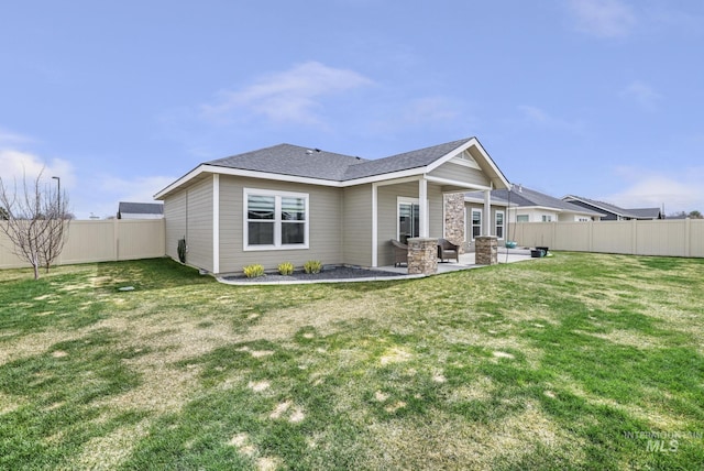 back of property with a yard, a fenced backyard, a shingled roof, and a patio