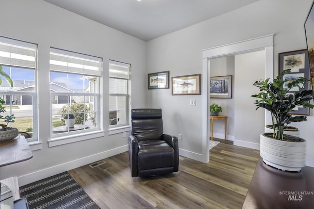 living area featuring visible vents, dark wood-style flooring, and baseboards