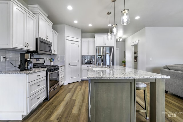 kitchen with a sink, appliances with stainless steel finishes, white cabinetry, and dark wood-style flooring