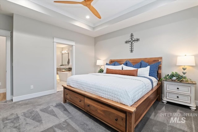 carpeted bedroom with a raised ceiling, baseboards, recessed lighting, ensuite bath, and a ceiling fan