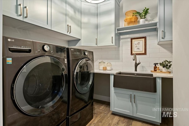 laundry room with separate washer and dryer, cabinet space, and wood finished floors