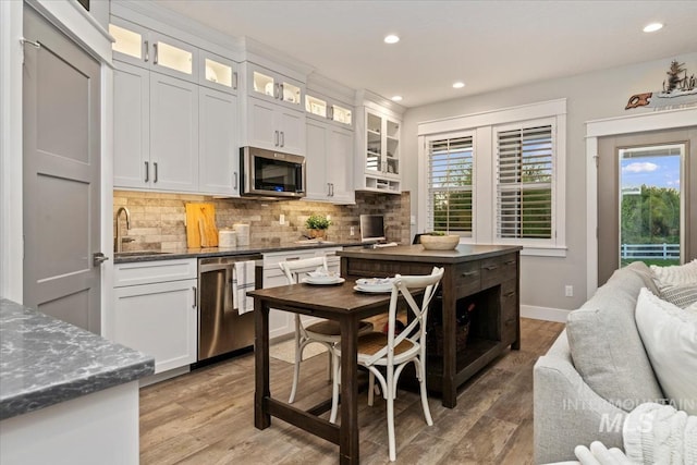 kitchen featuring stainless steel appliances, a sink, tasteful backsplash, light wood-style floors, and recessed lighting