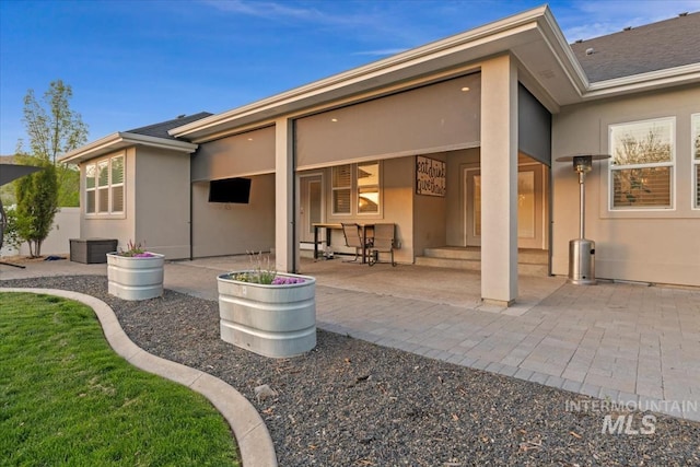 rear view of house featuring stucco siding and a patio area