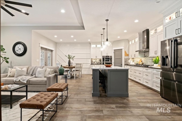 kitchen with appliances with stainless steel finishes, wall chimney range hood, recessed lighting, backsplash, and a kitchen island