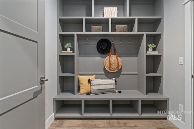 mudroom with baseboards, wood finished floors, and built in shelves