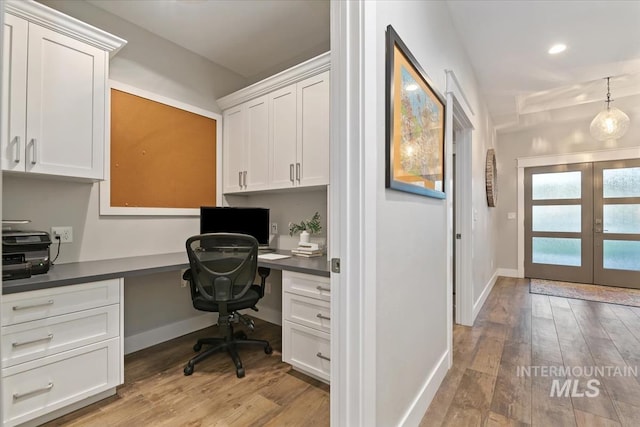 office space with built in desk, light wood-style floors, french doors, and recessed lighting