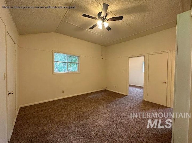 carpeted spare room featuring ceiling fan and vaulted ceiling