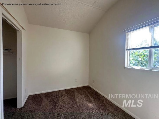 unfurnished bedroom featuring a textured ceiling, carpet floors, and vaulted ceiling