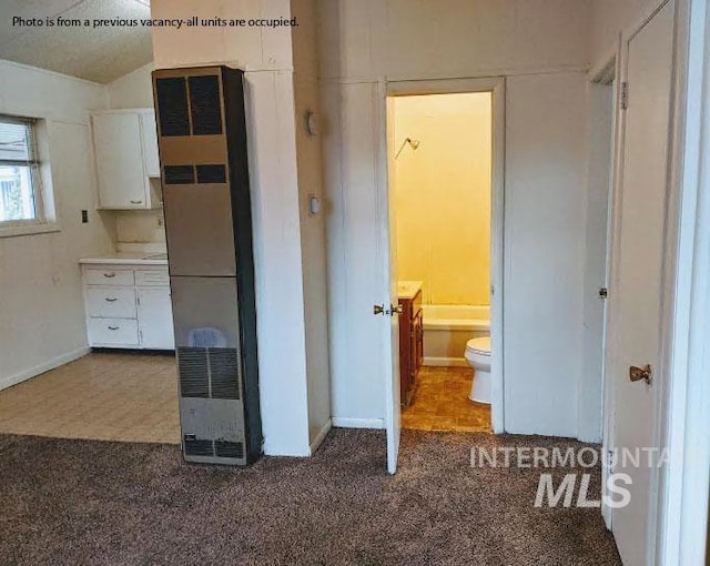 interior space featuring dark colored carpet, refrigerator, and white cabinetry