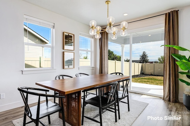 dining area featuring light wood finished floors, baseboards, and an inviting chandelier