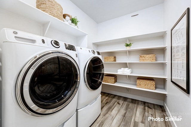 laundry room with independent washer and dryer, light wood-style flooring, visible vents, and laundry area