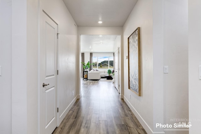 hall featuring baseboards, wood finished floors, and recessed lighting