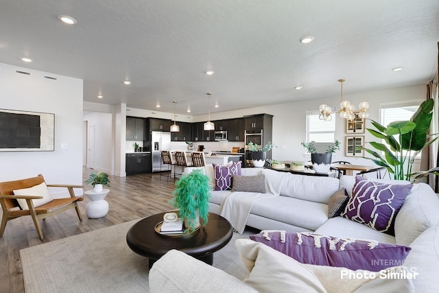 living area featuring a chandelier, wood finished floors, and recessed lighting