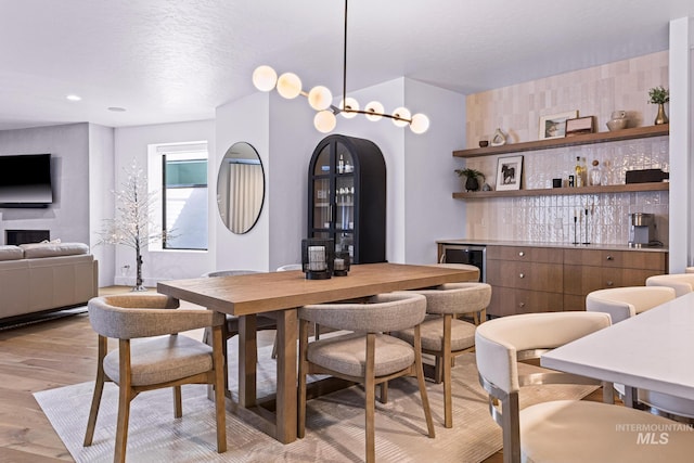 885 E Joplin Ln, Eagle, ID 83616 - dining area featuring bar, light wood finished floors, wine cooler, a textured ceiling, and arched walkways