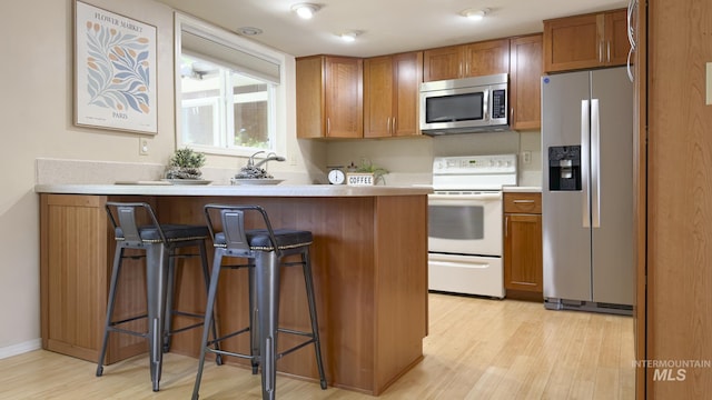 11254 W Camas St, Boise, ID 83709 - kitchen featuring stainless steel appliances, light wood-type flooring, brown cabinets, a breakfast bar area, and a peninsula