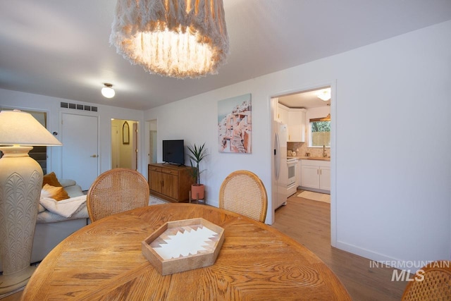 dining room featuring light wood-style floors, visible vents, and a chandelier