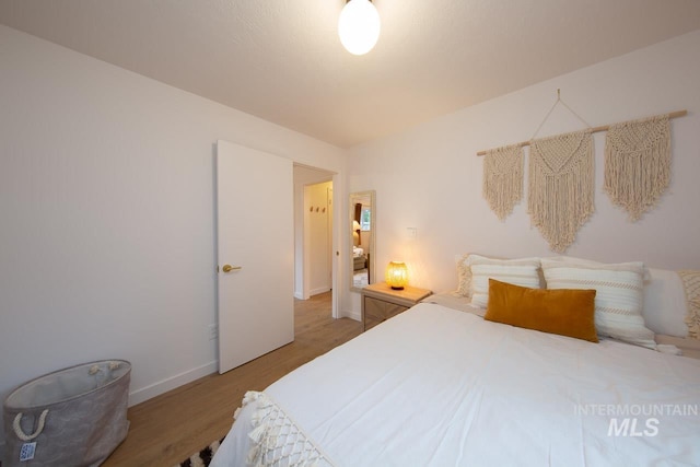 bedroom featuring baseboards and light wood finished floors