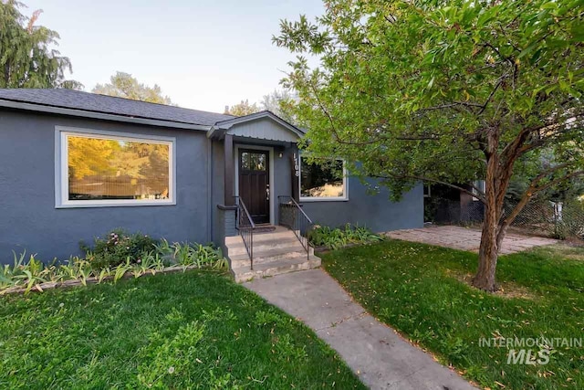 view of front of house featuring stucco siding, a patio area, and a front yard