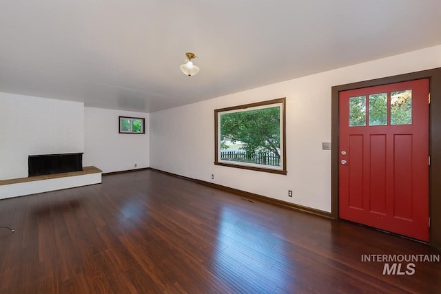 entryway with a healthy amount of sunlight, a brick fireplace, and wood finished floors