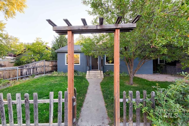 view of front of home featuring fence, a front lawn, and stucco siding