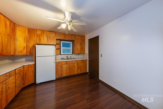 kitchen with ceiling fan, brown cabinets, dark wood-style flooring, freestanding refrigerator, and light countertops