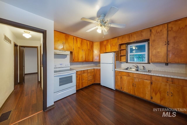 kitchen with white appliances, a sink, visible vents, and under cabinet range hood