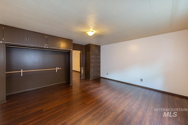 unfurnished living room featuring dark wood-style floors and baseboards