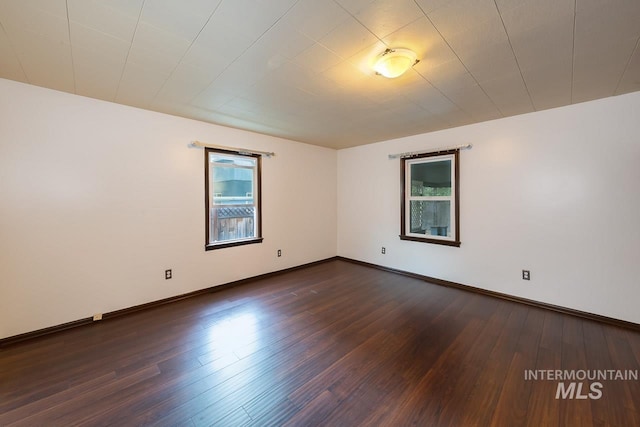 empty room with dark wood-type flooring and baseboards