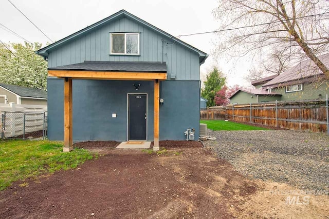 rear view of house featuring board and batten siding and fence