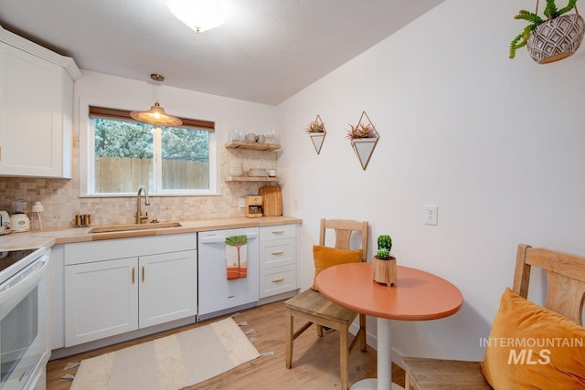 kitchen with light wood finished floors, backsplash, white cabinets, a sink, and white appliances