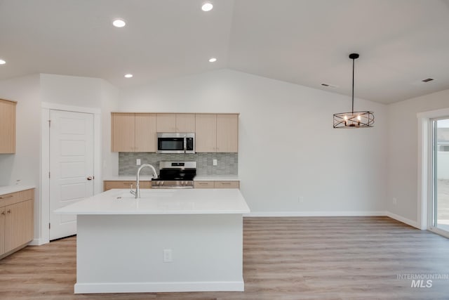 kitchen with appliances with stainless steel finishes, sink, light brown cabinetry, and an island with sink