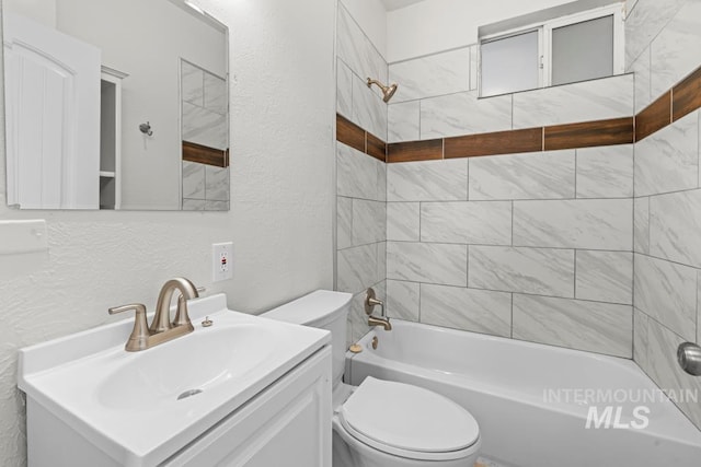 full bathroom with toilet, tiled shower / bath combo, and vanity