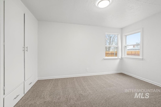 spare room with a textured ceiling and carpet flooring