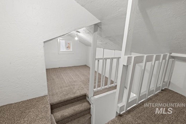 interior space featuring vaulted ceiling, carpet flooring, and a textured ceiling