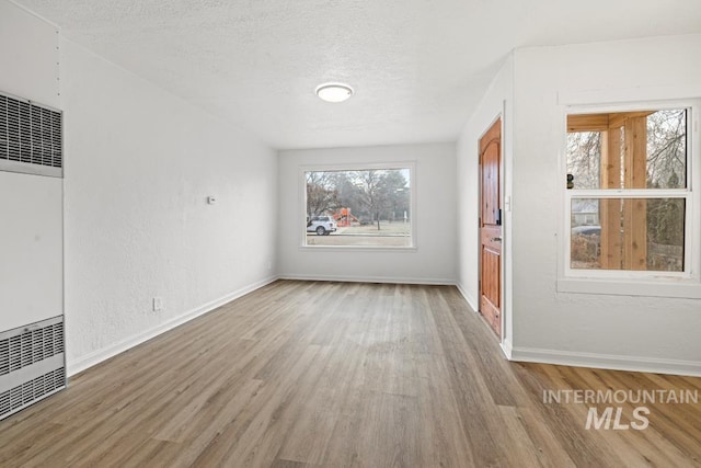 spare room with light wood-type flooring and a textured ceiling