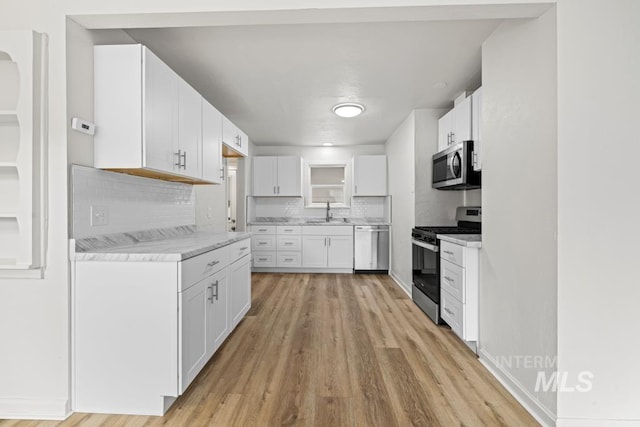 kitchen with decorative backsplash, appliances with stainless steel finishes, sink, and white cabinetry