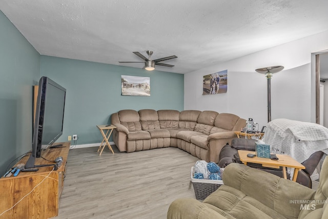 living room featuring light wood finished floors, baseboards, and a ceiling fan