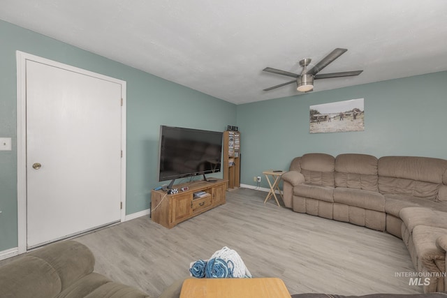 living room featuring ceiling fan, baseboards, and wood finished floors