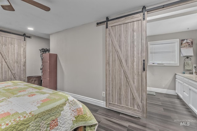 bedroom with a ceiling fan, recessed lighting, a barn door, baseboards, and wood finished floors