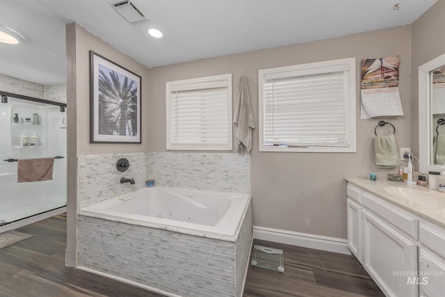 bathroom featuring a whirlpool tub, baseboards, a shower stall, vanity, and wood finished floors