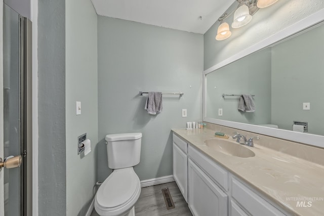 bathroom featuring toilet, baseboards, vanity, and visible vents