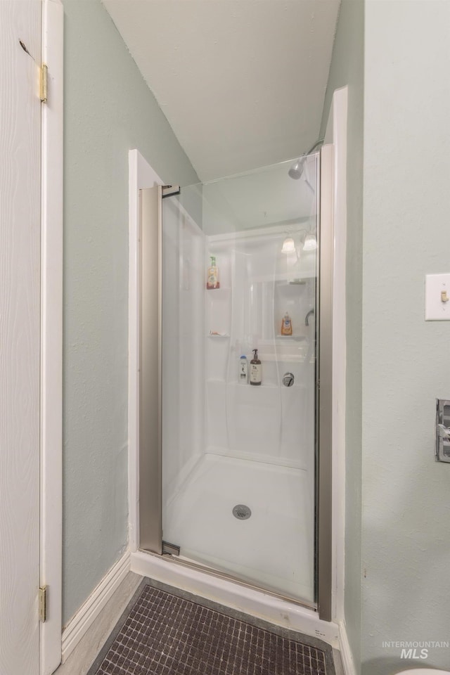 bathroom with baseboards and a shower stall